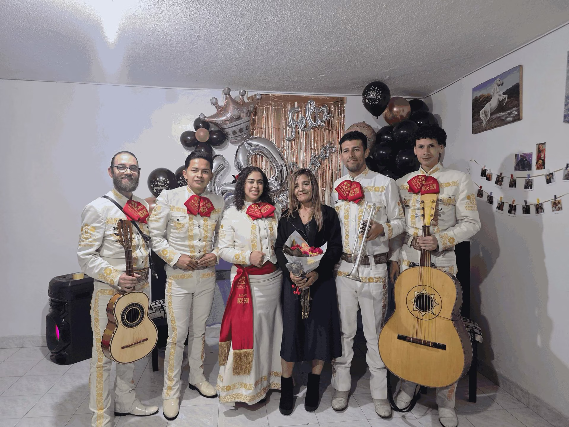 Grupo de mariachis en Bogotá Norte cantando serenata de cumpleaños junto a la festejada con ramo de flores